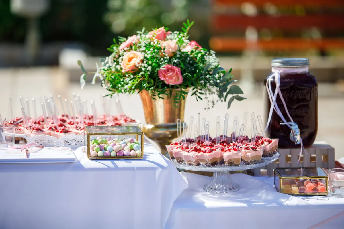 Mesa de dulces para boda con flores y frascos de cristal